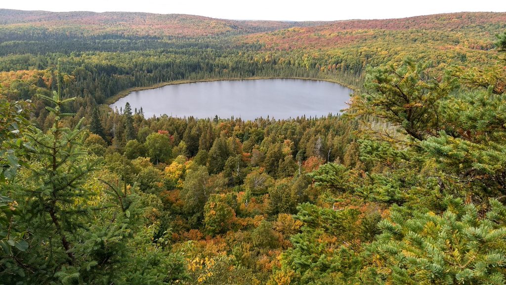 small lake nestled in hills with fall color
