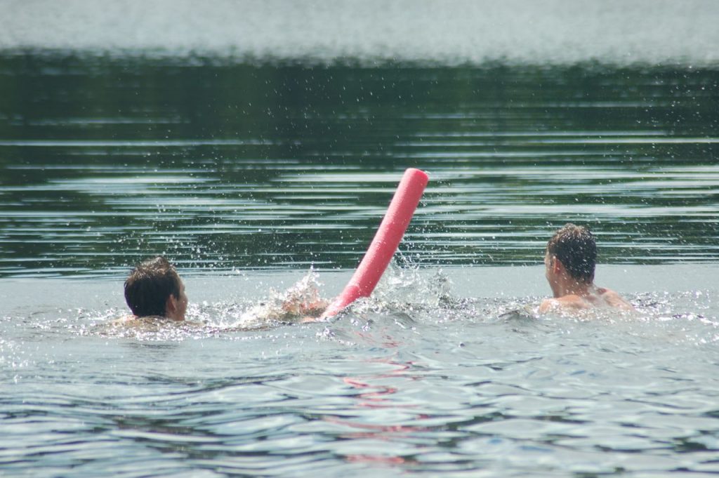 two boys swimming with a pool noodle in Bow Lake at Okontoe