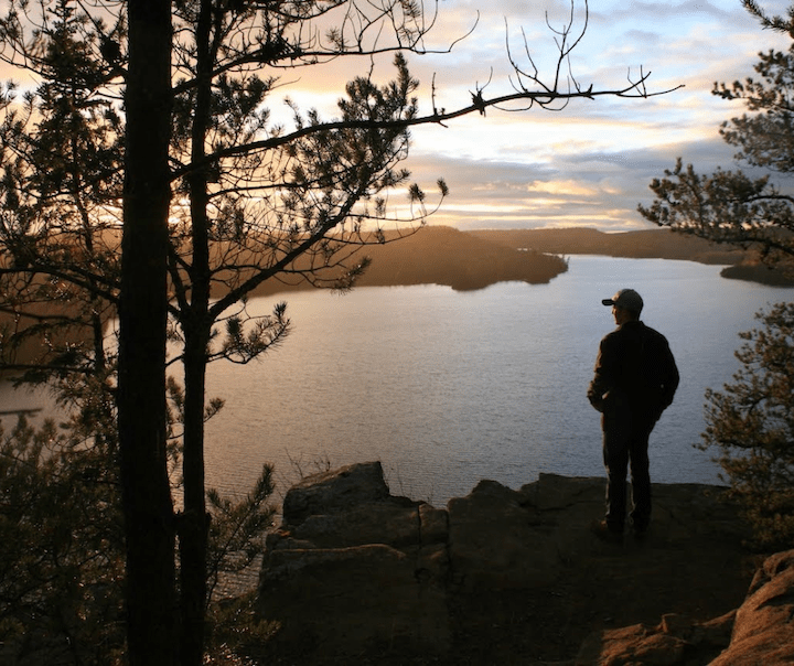 man standing up on Honeymoon Bluff, overlooking Hungry Jack lake at sunset
