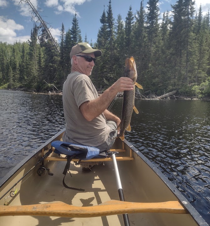 man holding a northern pike he just caught from Quiver Lake at Okontoe
