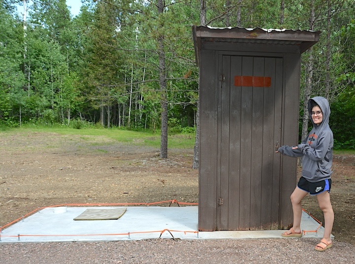 old Okontoe outhouse with woman standing next to it