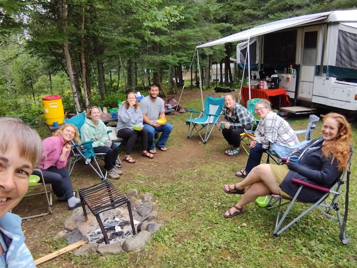 a group of friends talk together at a campsite