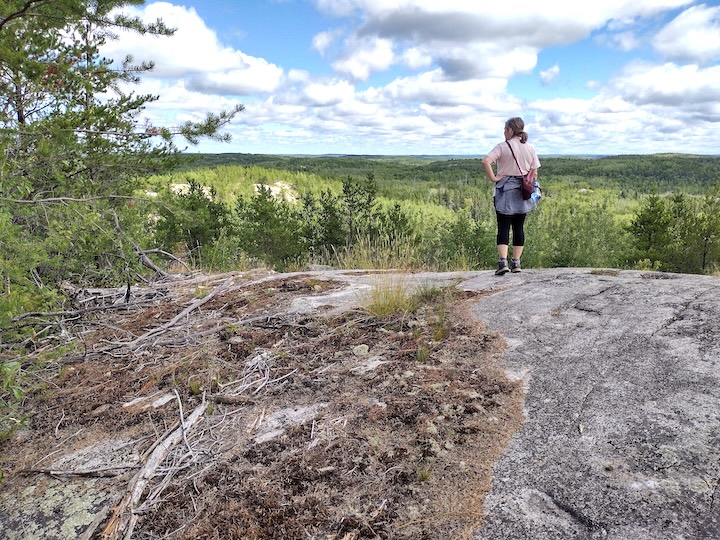 woman stands overlooking the distant forested hills