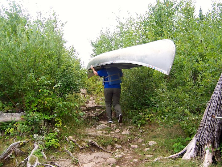 woman portages an alumnium canoe in the Boundary Waters