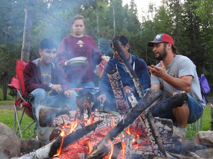 several adults and a teen boy around Okontoe's community campfire