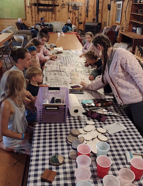 a couple of adults supervise kids' crafts in the Dining Hall at Okontoe