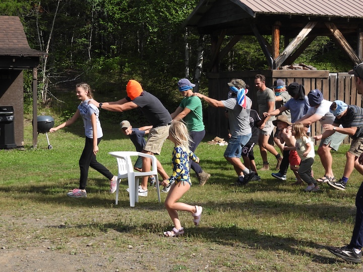 kid and dad game during family camp - kids guiding their blindfolded dad around obstacles