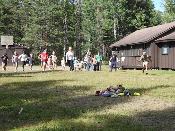 a bunch of kids run to a pile of shoes during a family game