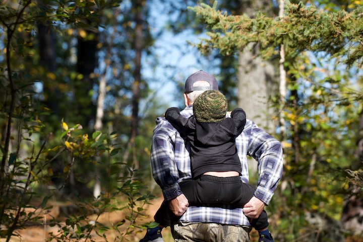 grandpa gives little grandson a piggy back through the woods