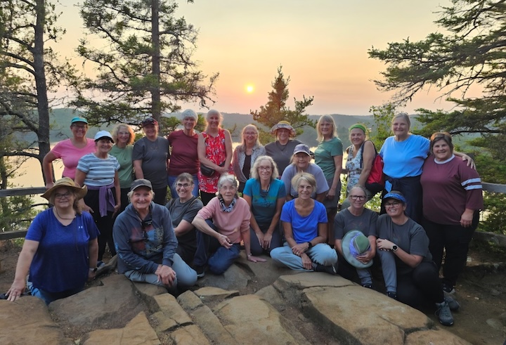 group of women at Honeymoon Bluff, northern Minnesota, with the sun setting behind them