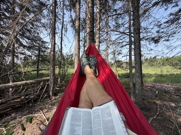 a bible and relaxed legs of a woman sitting in a hammock with beauty beyond