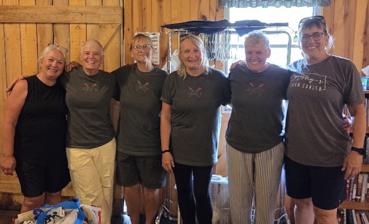 six smiling ladies stand together inside Okontoe's dining hall